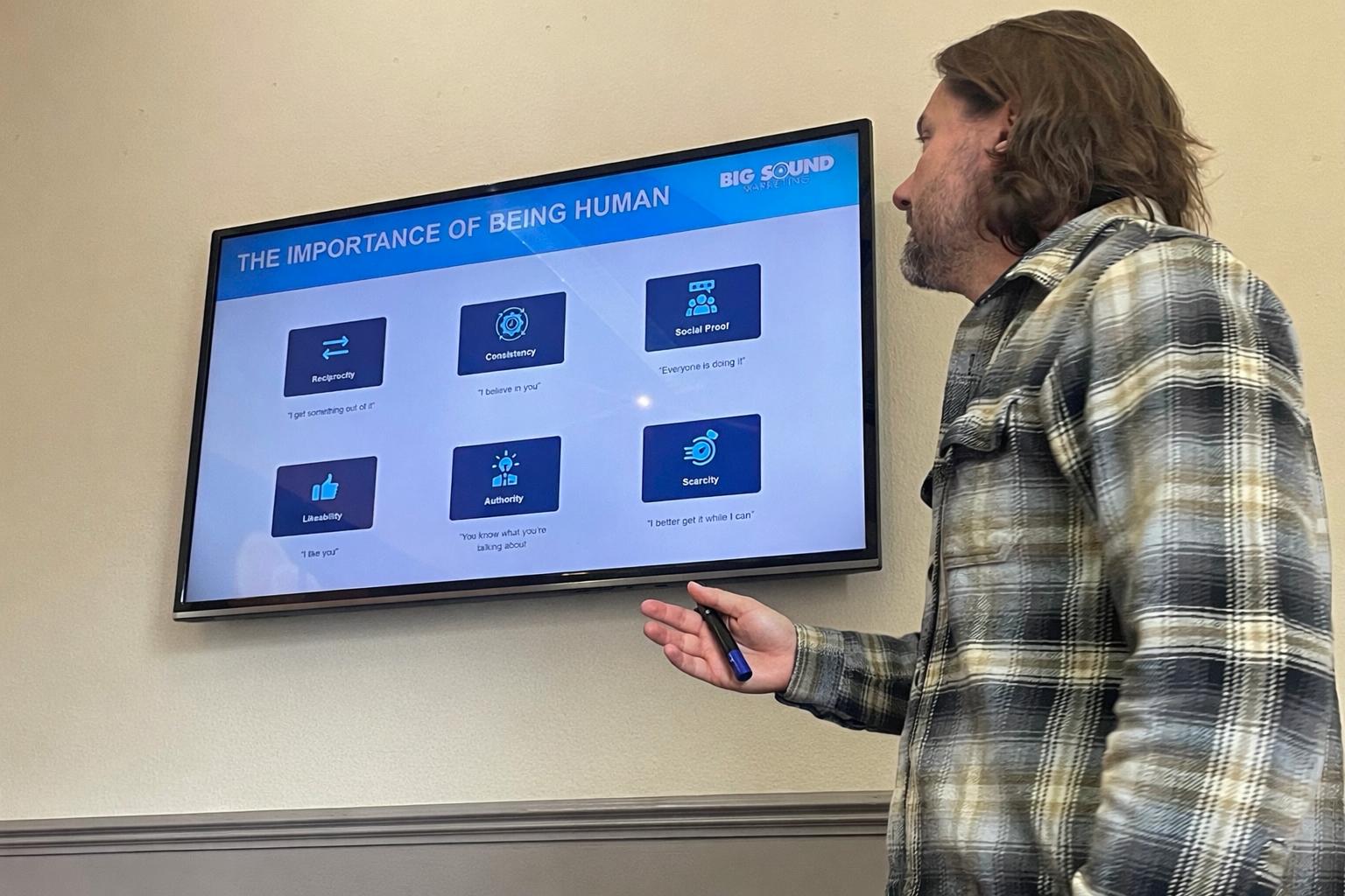 A man standing presenting in front of a screen.